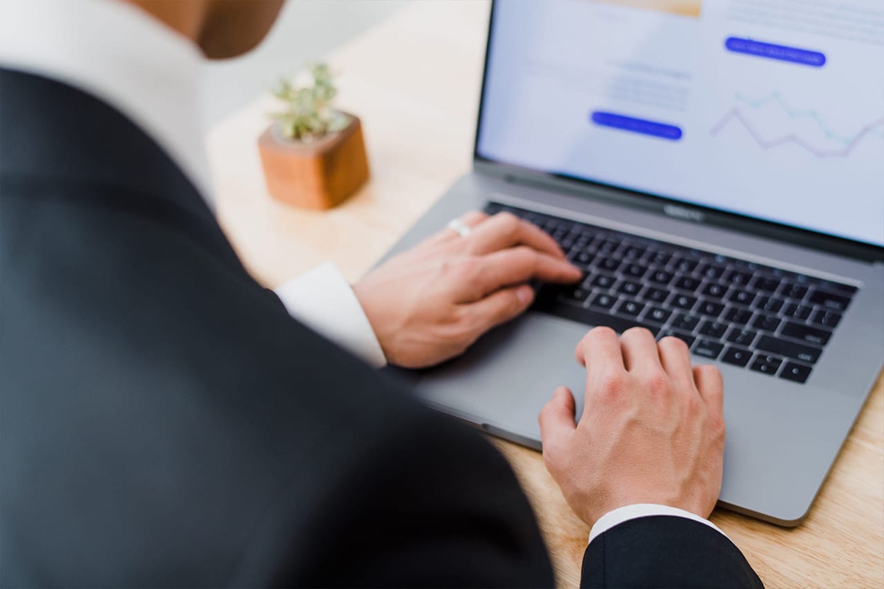 a man 's hand typing on a grey laptop a man 's hand typing on a grey laptop