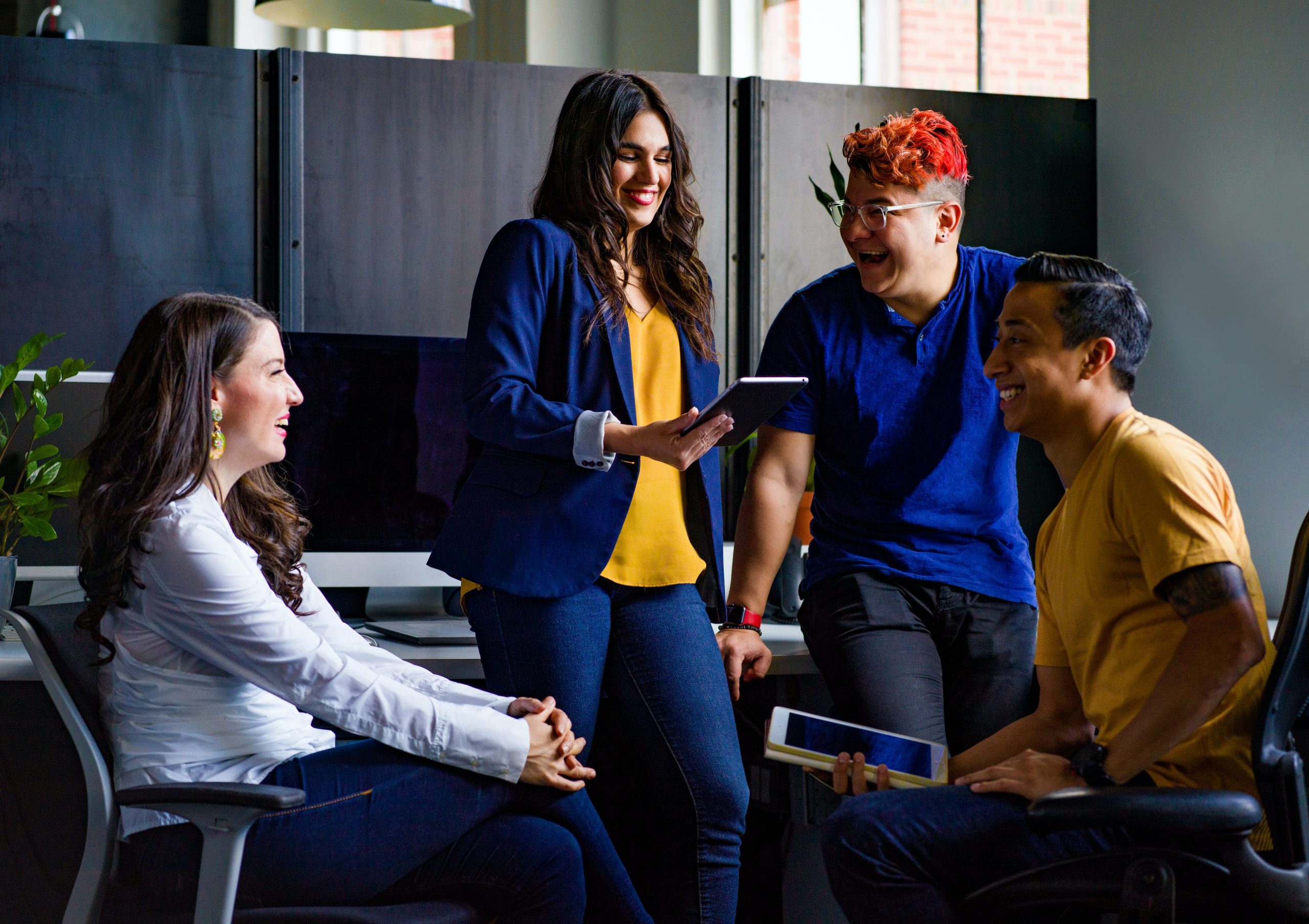 four people in a room talking to each other and smiling wearing bright blue and yellow clothes