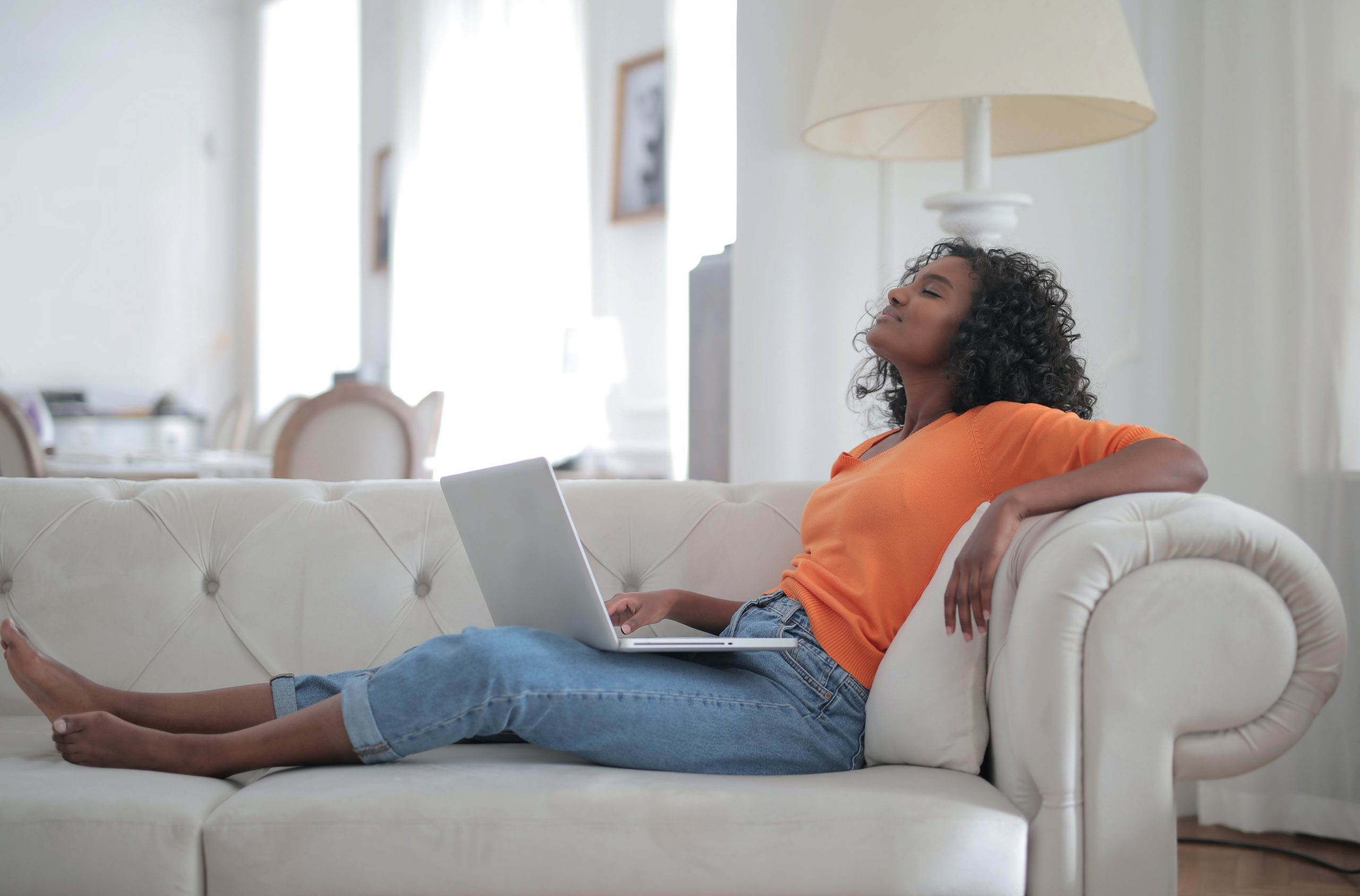 a woman sitting on a sofa holding a laptop