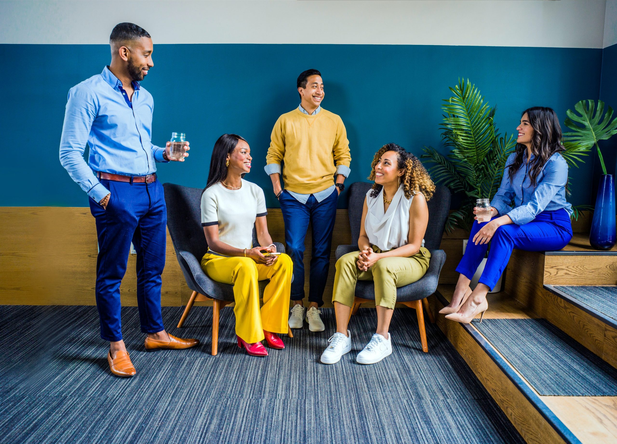 a group of men and women sitting on chairs and talking to each other