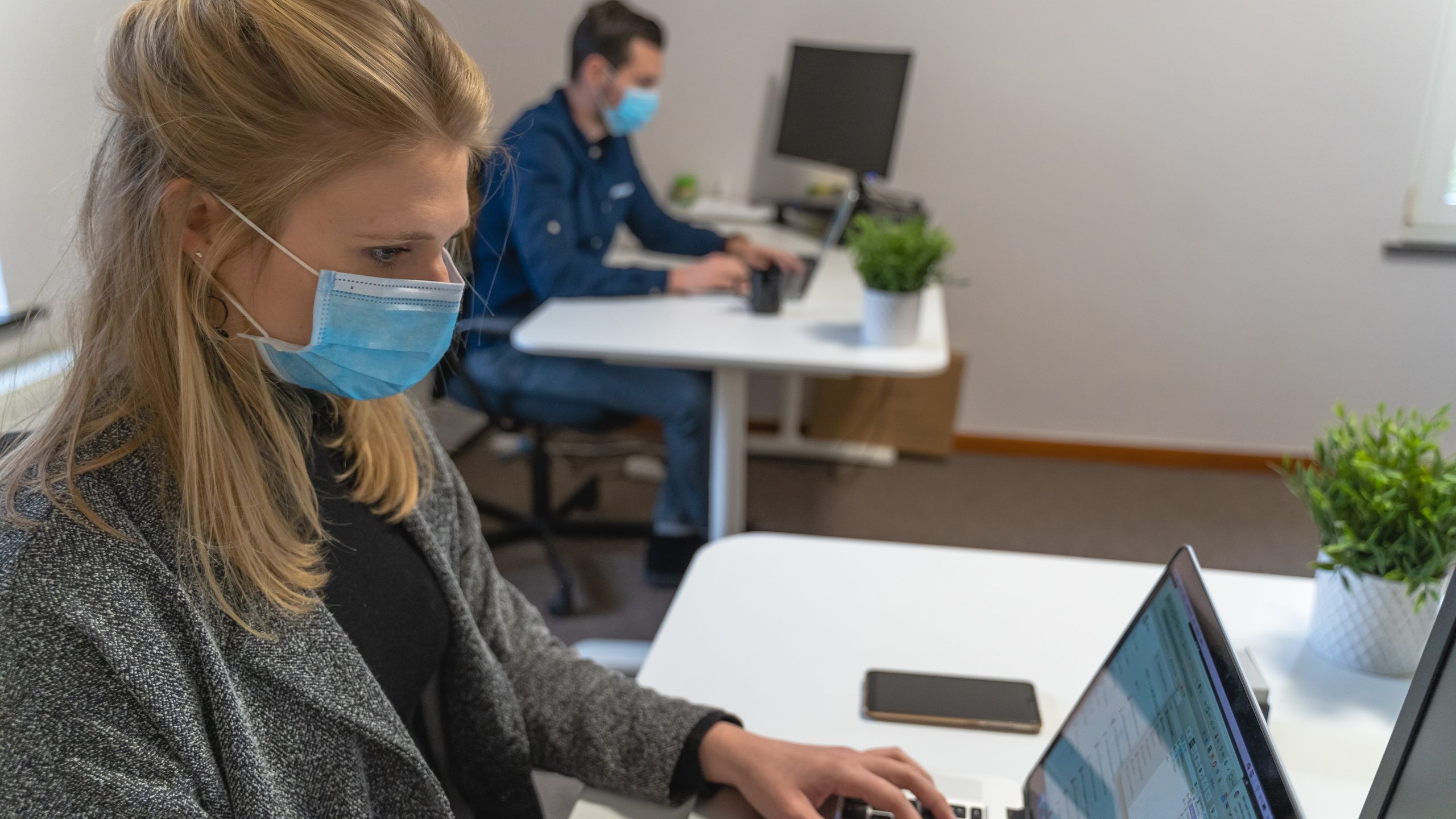 a woman working on her laptop wearing a mask