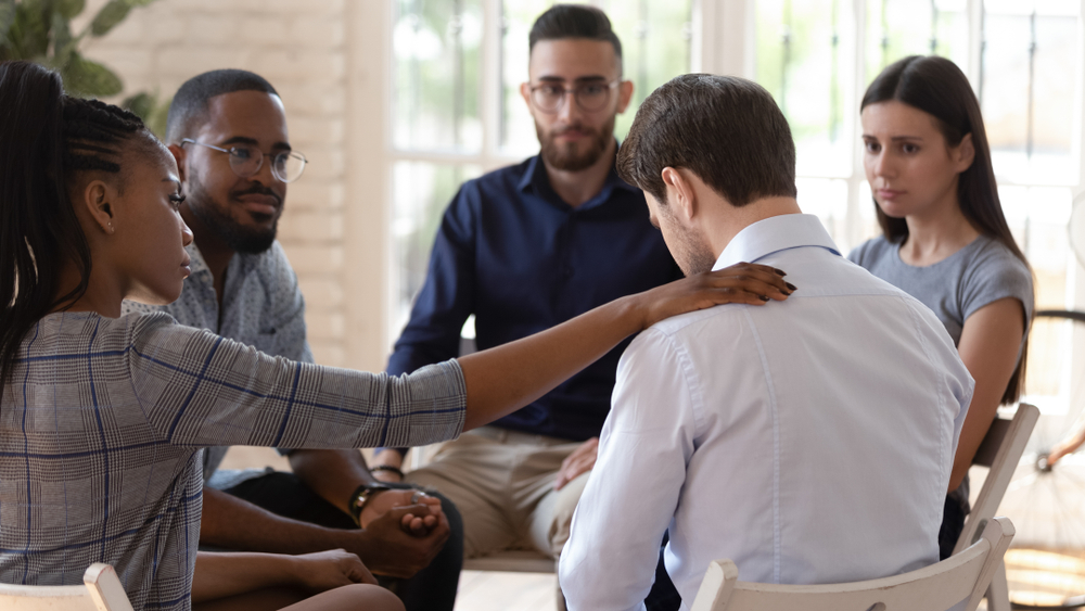 Rear,View,At,Upset,Man,Feel,Pain,Depression,Problem,Addiction a group of employees sitting in a circle supporting each other