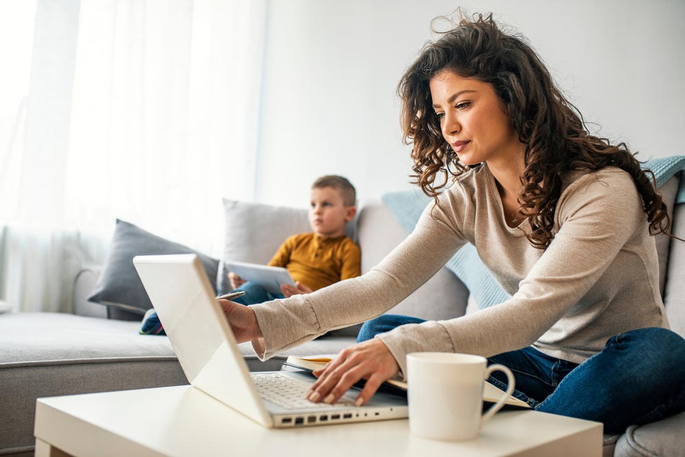 a mum and her son sitting on a couch in front of a laptop